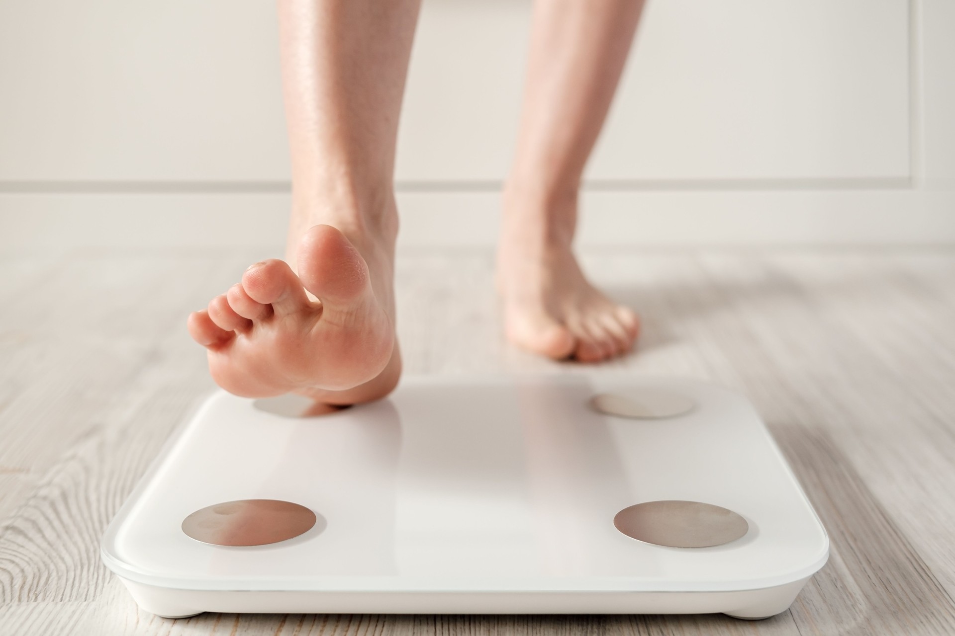 Woman foot takes a step onto a smart scale that makes bioelectric impedance analysis, BIA, body fat measurements.