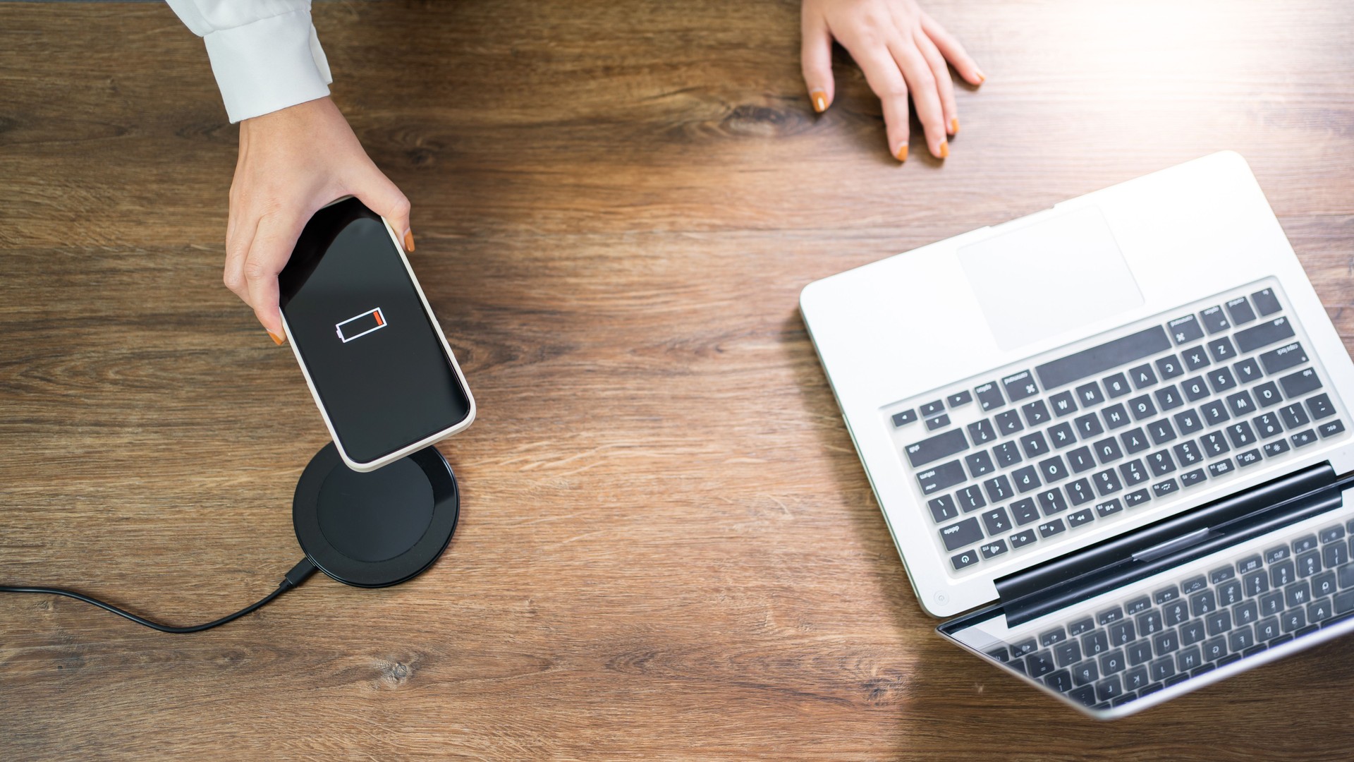 Charging mobile phone battery with wireless charging device in the table. Smartphone charging on a charging pad. Mobile phone near wireless charger Modern lifestyle technology concept.